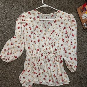 A cream faux-wrap shirt with red floral design.